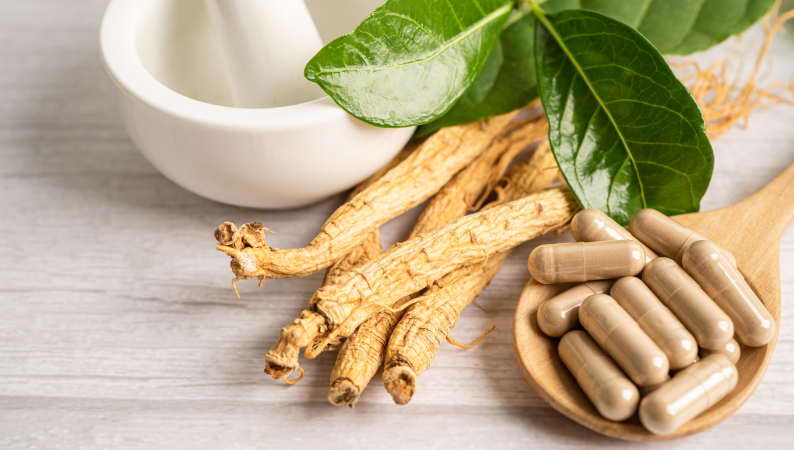 Korzeń żeń-szenia i kapsułki obok moździerza – porównanie adaptogenów w kontekście wyboru: ashwagandha czy żeń-szeń.