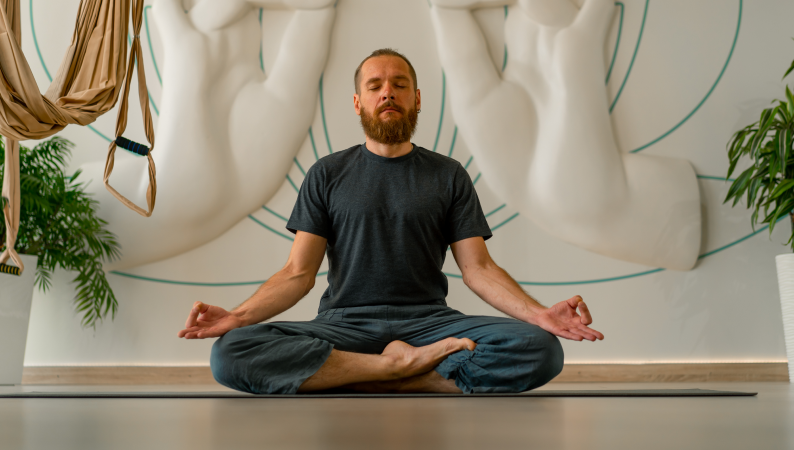 Mężczyzna w pozycji medytacyjnej podczas praktyki jogi – idealny moment, by wspierać się naturalnie dzięki adaptogenom dla joginów.