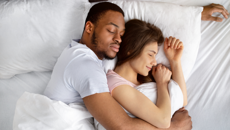 Para śpiąca w objęciach w białej pościeli – spokojny sen a odporność organizmu.