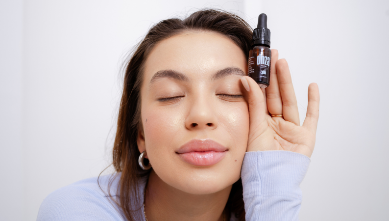 Kobieta zrelaksowana z zamkniętymi oczami trzymająca butelkę olejku – naturalne wsparcie CBD na lęk uogólniony.