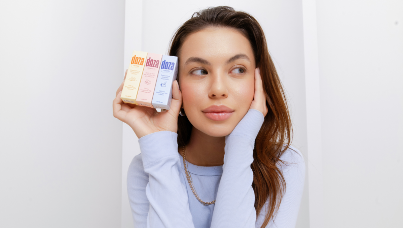 Kobieta trzymająca suplementy Doza – naturalne adaptogeny wspierające spokój, energię i zdrowy styl życia.