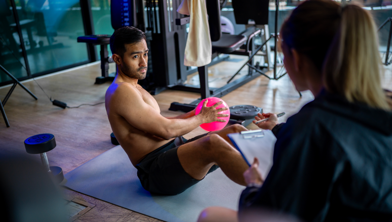 Trenujący mężczyzna wykonujący ćwiczenia na macie w siłowni, pokazujący wysiłek i kontekst CBD a regeneracja po treningu.